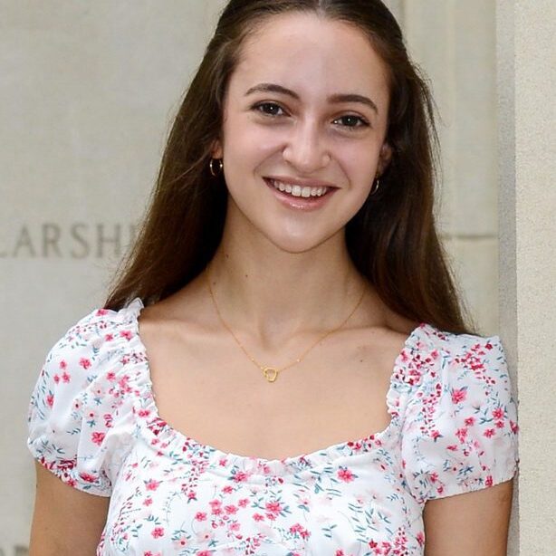 A young woman in floral dress smiling for the camera.